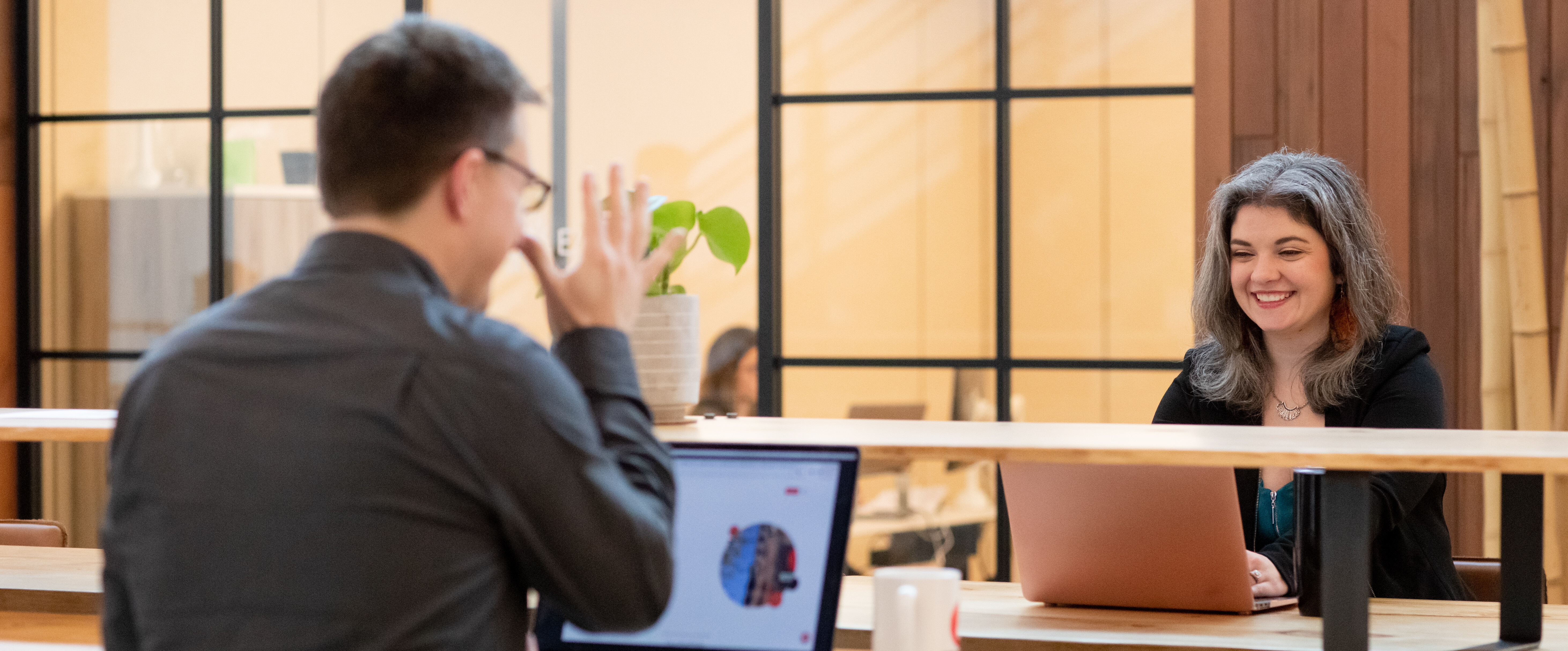 A man and woman engage in a friendly conversation at a modern workspace.