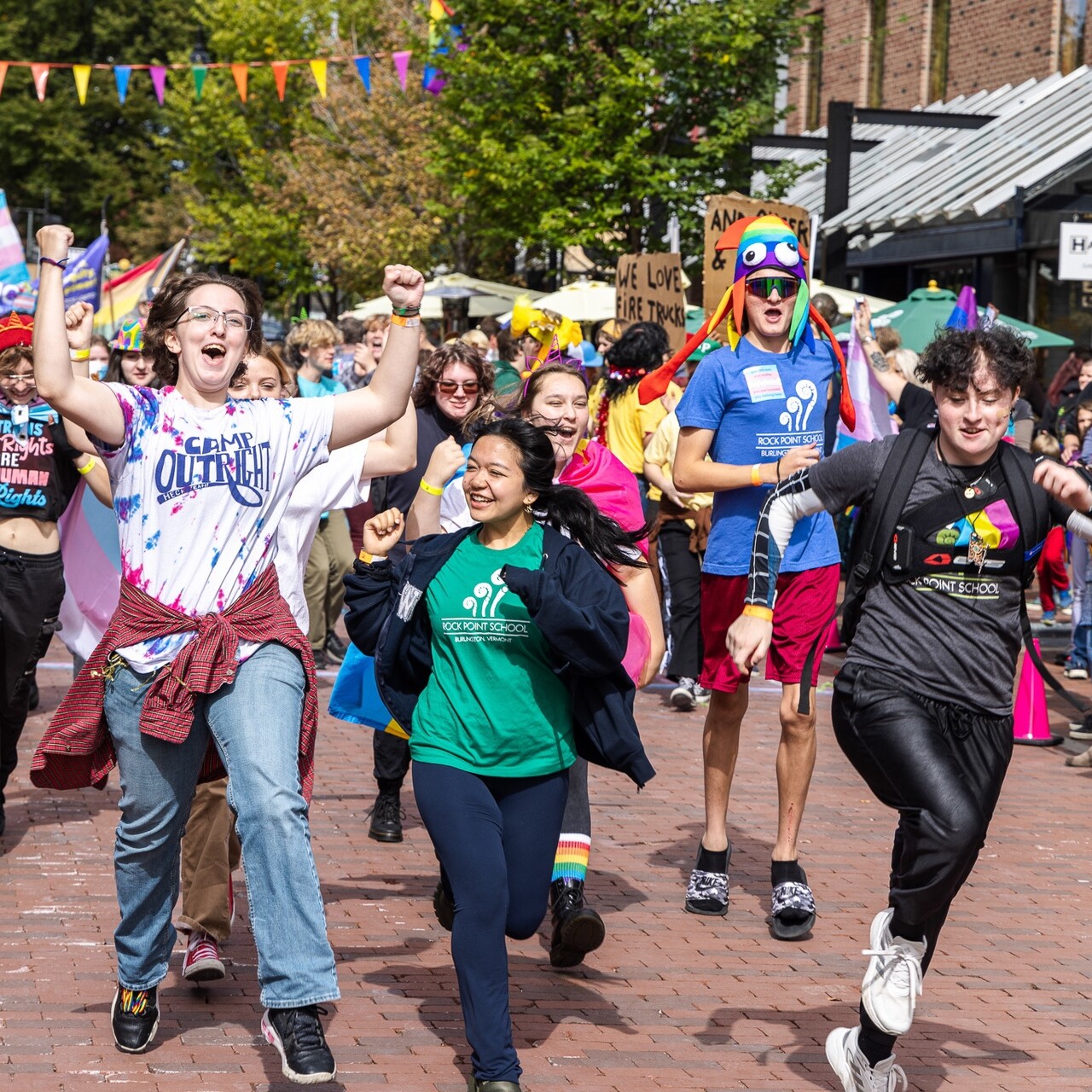 A lively group of young people joyfully marching in a parade, celebrating diversity.