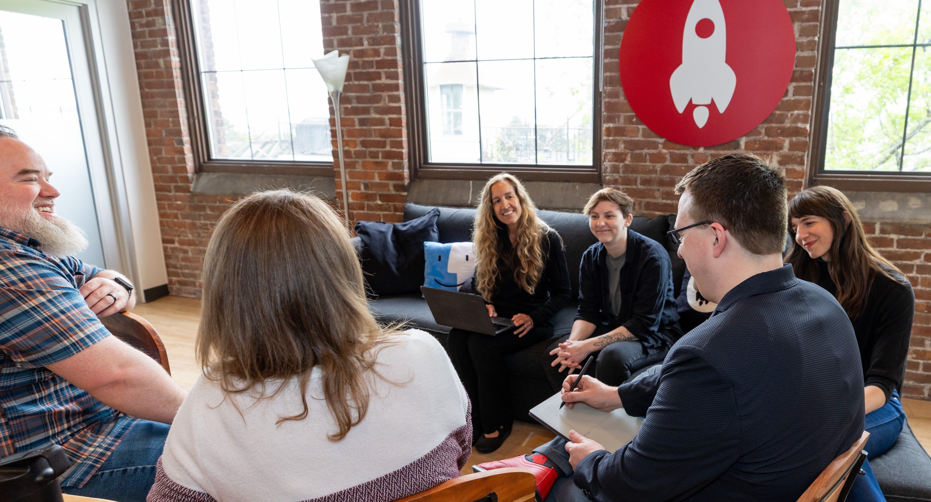 A group of six people collaborates in a bright, modern workspace.