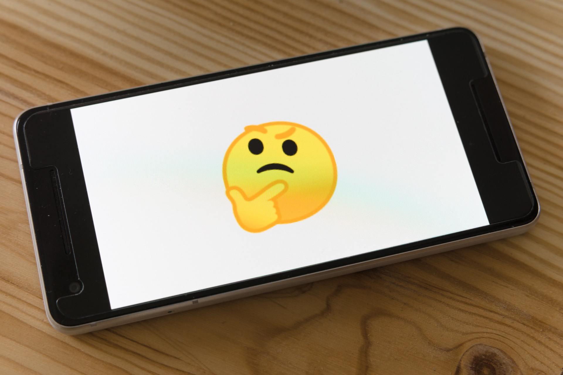 Phone with a curious face emoji on the screen