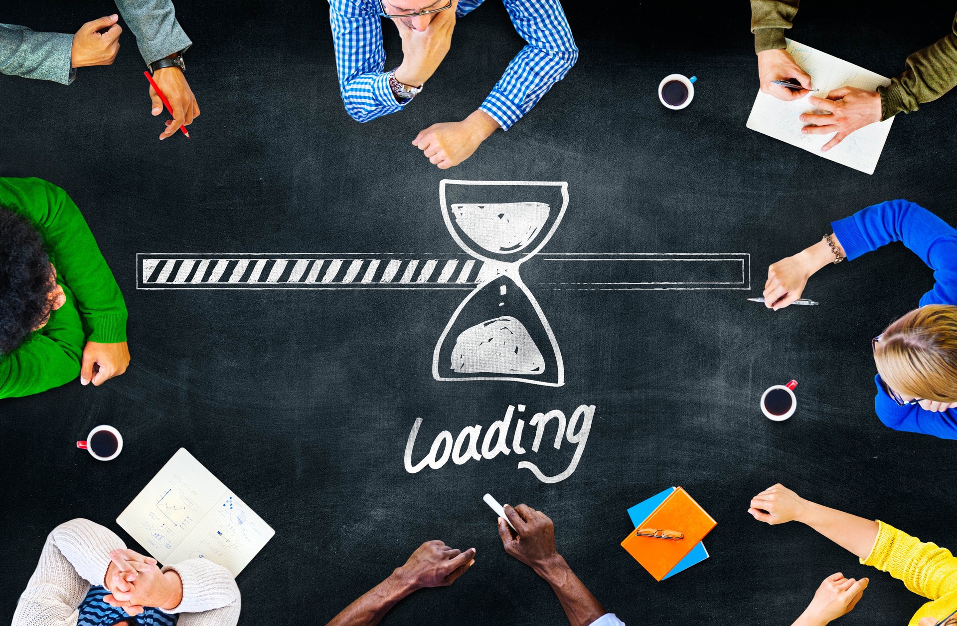 A group of people sit around a table that displays the text "Loading" with an hour glass.