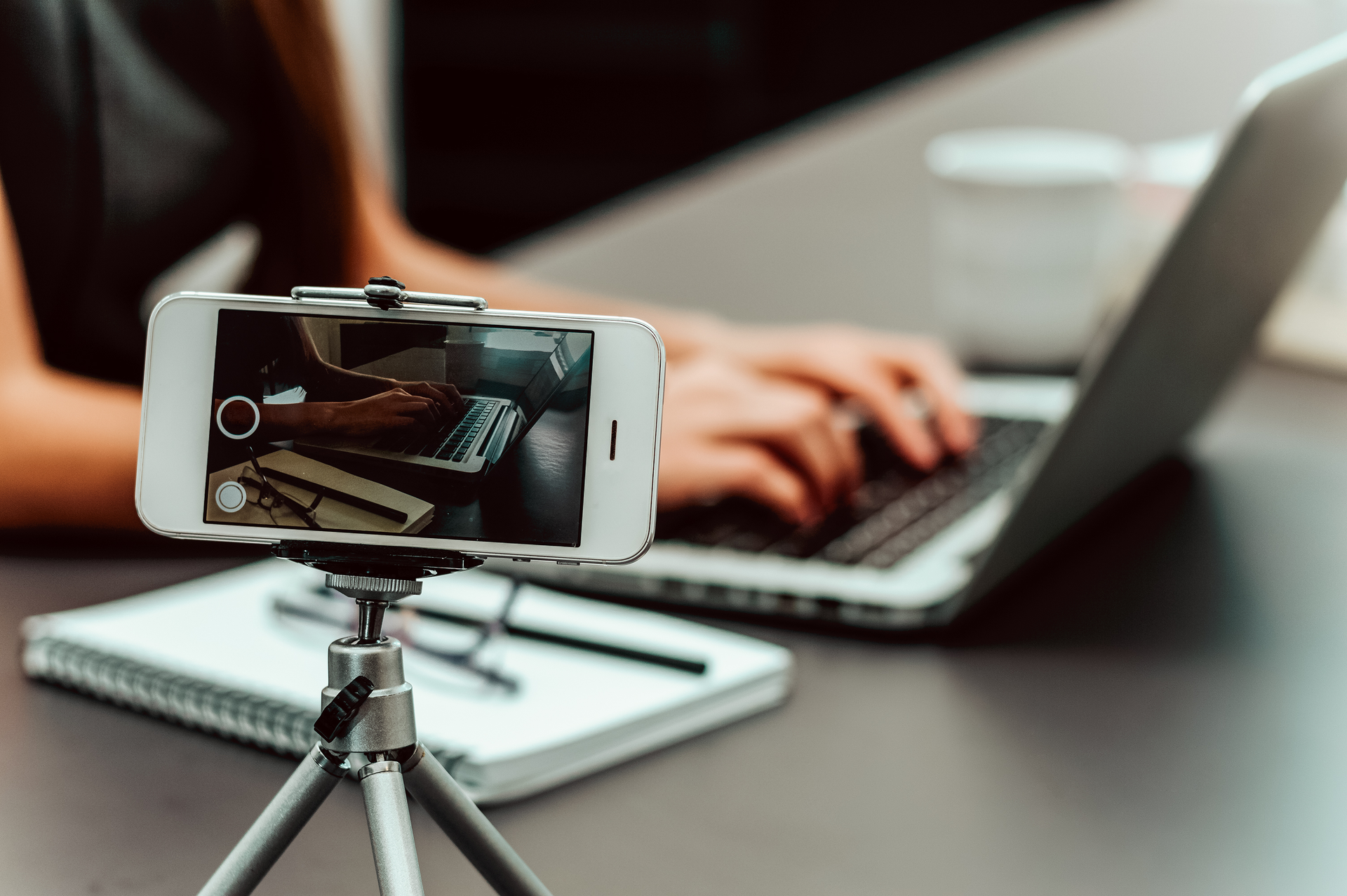 Mobile phone on tripod filming a person typing